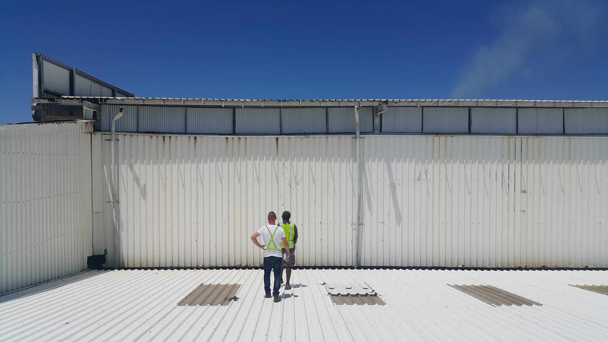 Two people reviewing a commercial metal roof